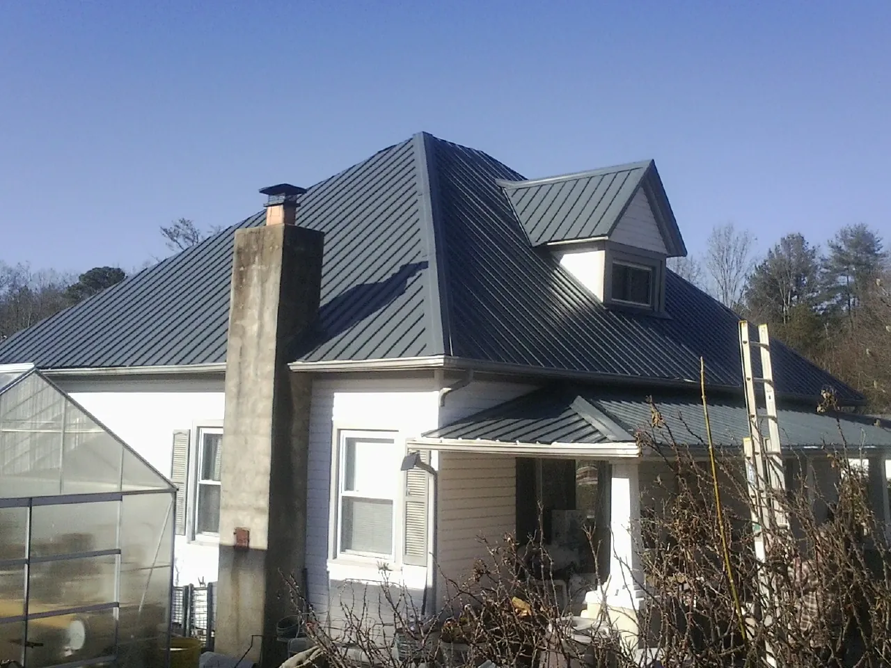 Dark blue standing seam metal roof on a white farmhouse with dormer — Slate & Tile Roof Repair by Roofing Brothers in Waleska