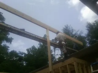 Carpenter setting a ridge beam over a new addition frame — Ice Dam Removal by Roofing Brothers in Waleska
