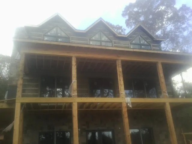 Dormers and porch framing on a large log home under construction — Roof Coating work by our crew in Waleska