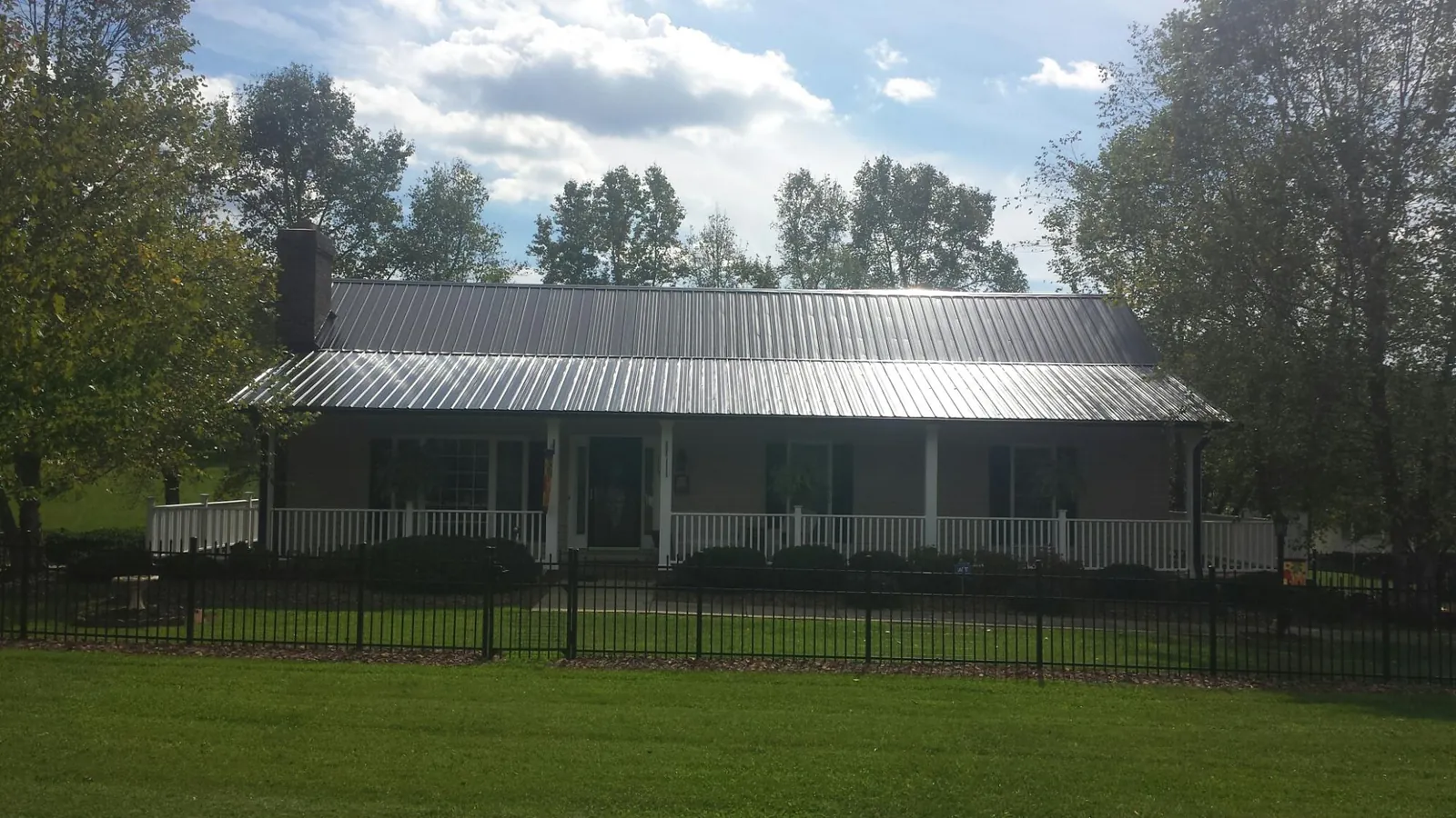 Gray metal roof on a brick ranch with a full width front porch — Gutter Guard Installation work by our crew in Waleska