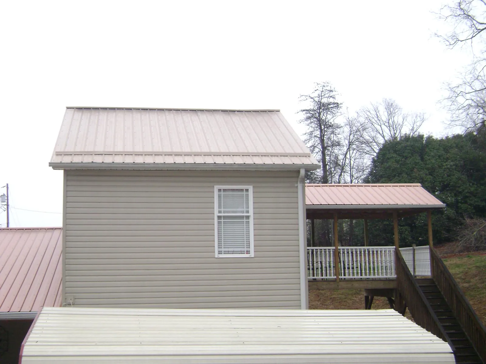 Tan metal roofs on a two story addition and attached porch, from a Roof Replacement job in Waleska