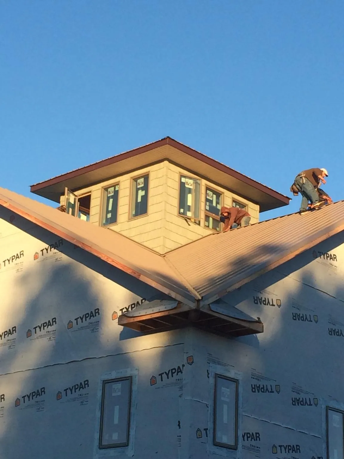 Roofers working around a rooftop cupola on a new metal roof at sunset — Roof Waterproofing in Waleska by Roofing Brothers